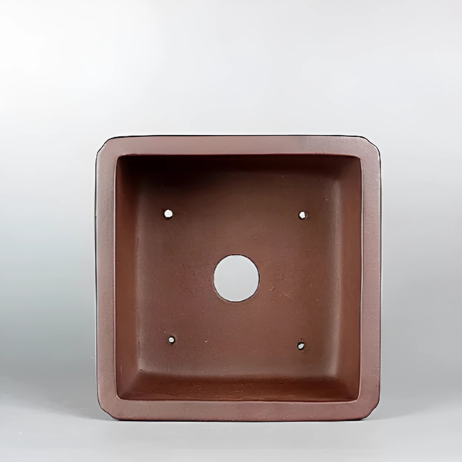 Brown handmade purple clay antique flower pot on a desktop.