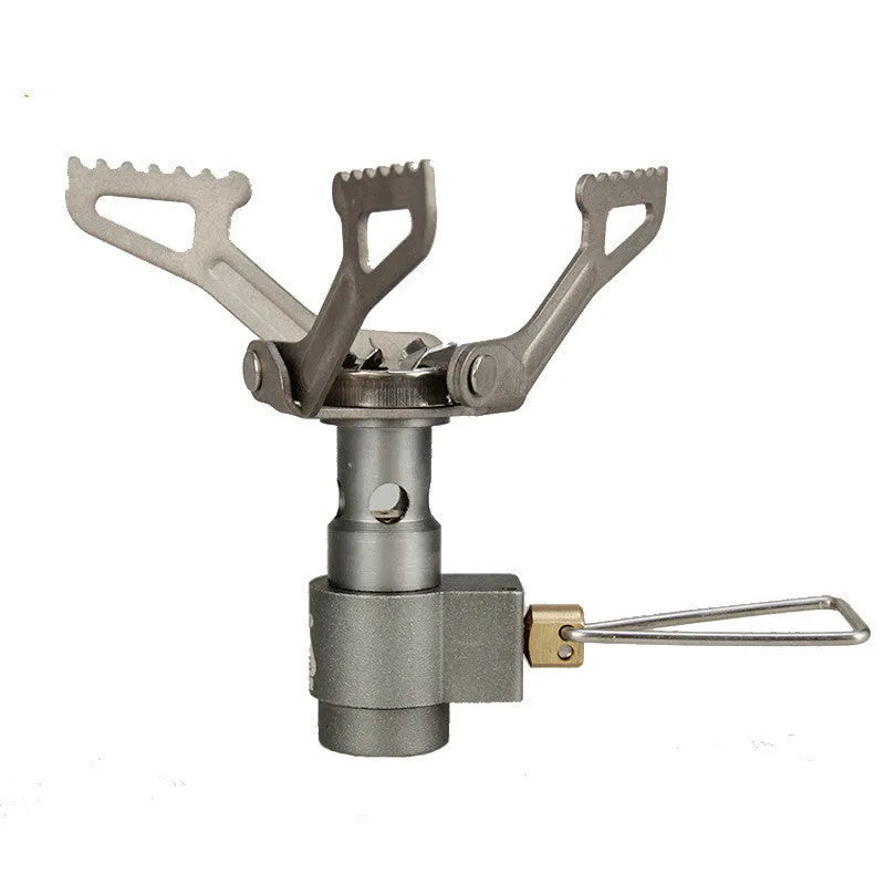 Compact one-piece propane camping stove on rocky ground, fuel canister attached, with a pot boiling.