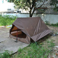 Brown and white pole-free A-line cabin tent for 2-3 people shown pitched with hiking poles.