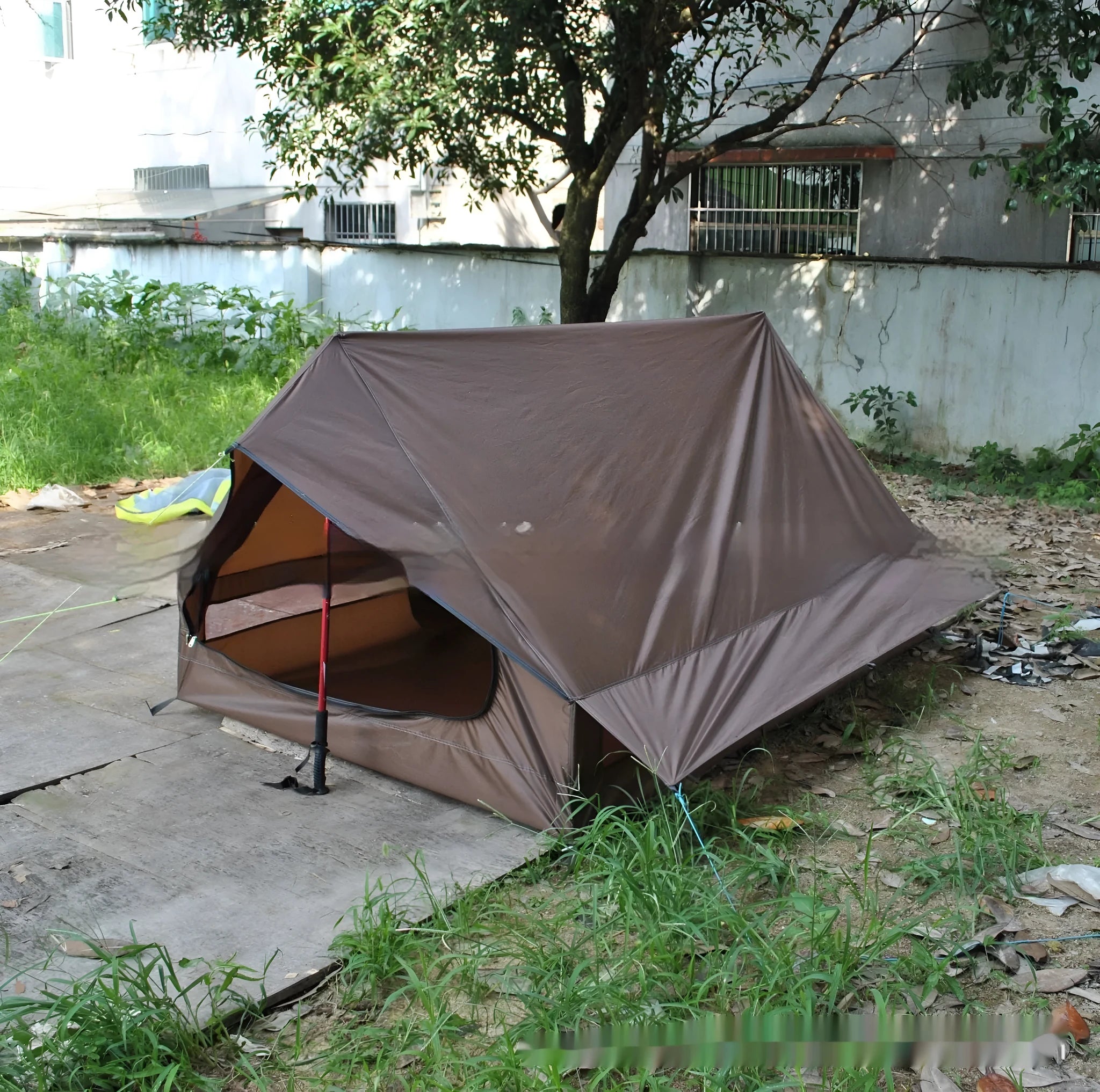 Brown and white pole-free A-line cabin tent for 2-3 people shown pitched with hiking poles.