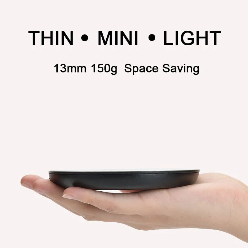 Black round desk cup warmer with tempered glass surface and low high switch on a wooden table.
