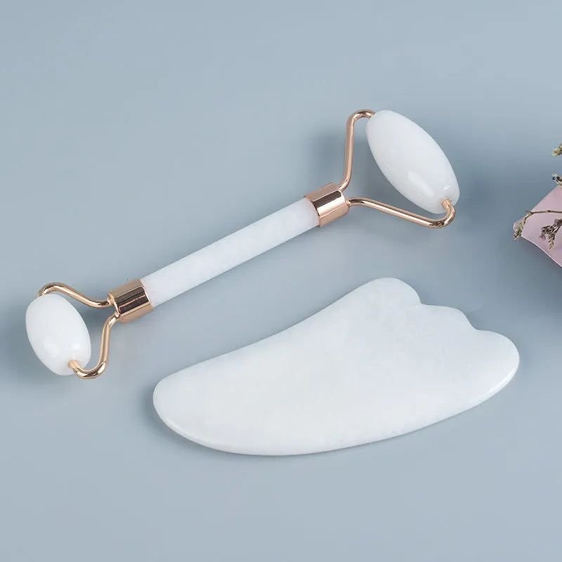 White jade facial roller and Gua Sha scraping board set on a neutral background.