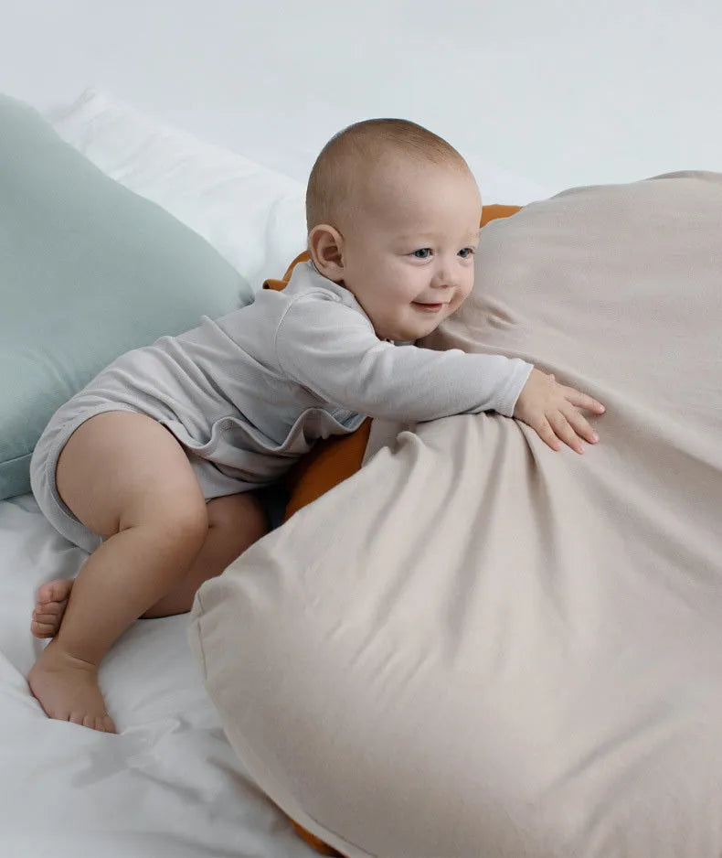 Beige portable baby nest cot crib for infants on a neutral background