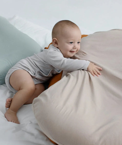 Beige portable baby nest cot crib for infants on a neutral background