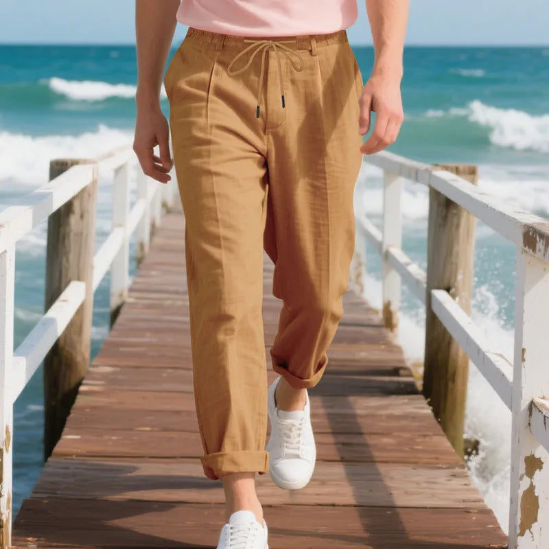 Man wearing light khaki linen casual trousers with a drawstring waist and straight-leg fit.