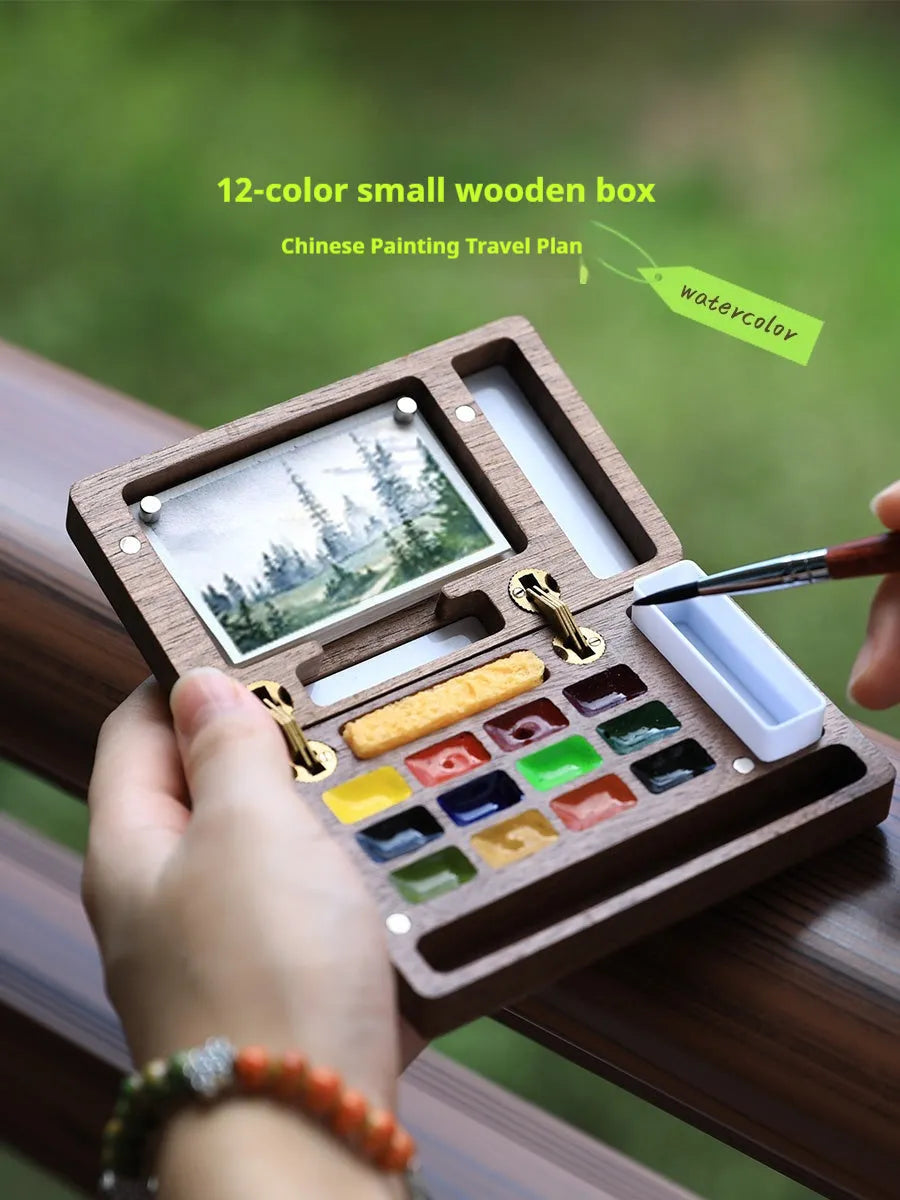Mini wooden watercolour paint box with walnut finish, open to show pigment suit selection.