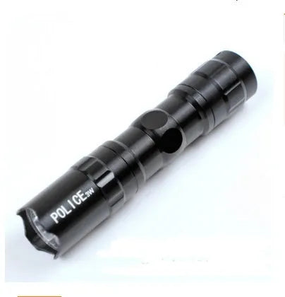 Black aluminium mini LED flashlight showing scale next to a AA battery.