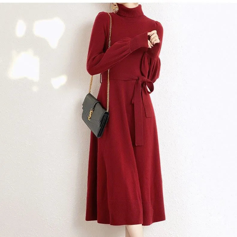 Woman wearing a rose red turtleneck knitted dress with long sleeves and a loose, flared big hem.