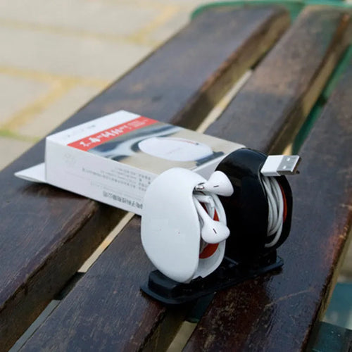 Automatic plastic cable winder retractor showing black, blue, and red units next to a coiled earphone cable.
