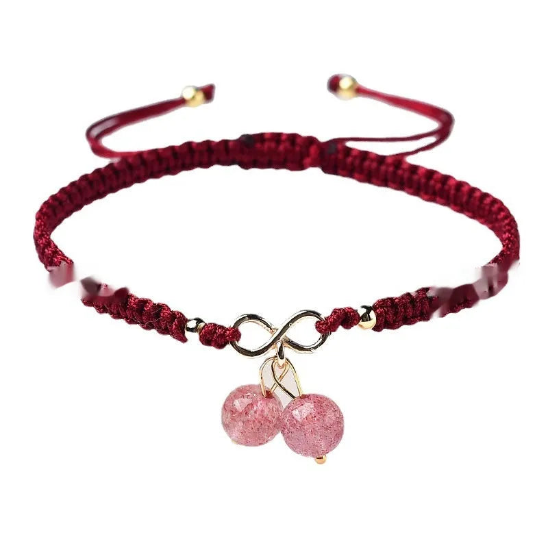 Close-up of a women's strawberry quartz bracelet with red cherry-shaped beads on a stretch cord.