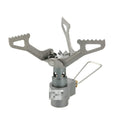 Compact one-piece propane camping stove on rocky ground, fuel canister attached, with a pot boiling.