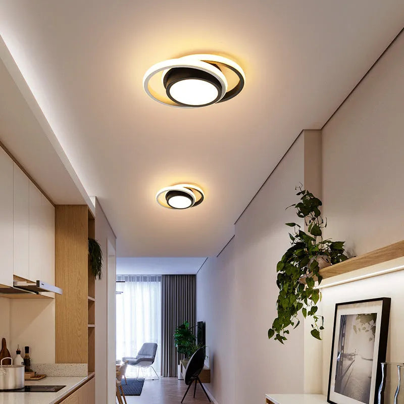Modern round aluminium ceiling light with integrated LEDs, shown illuminating an entrance hall.