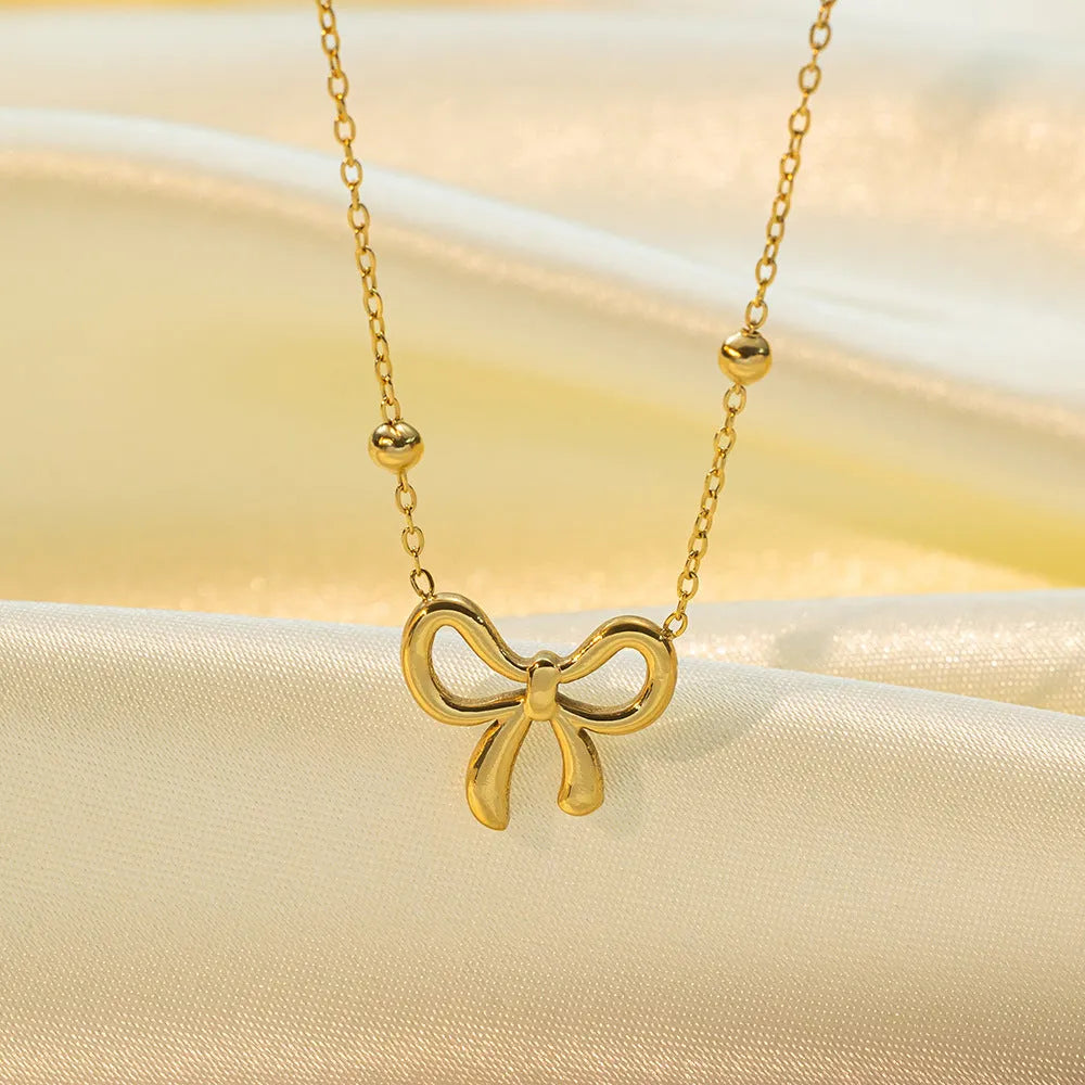 Gold bow necklace on adjustable cross chain for women