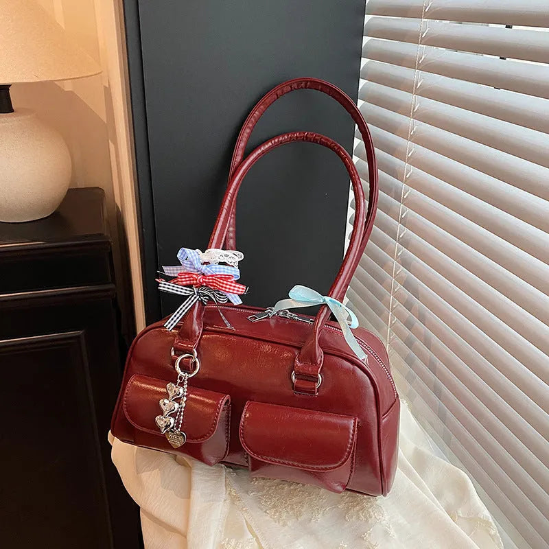 Retro-style brown PU leather women's pillow handbag with a one-shoulder strap, shown with a decorative ribbon pendant.