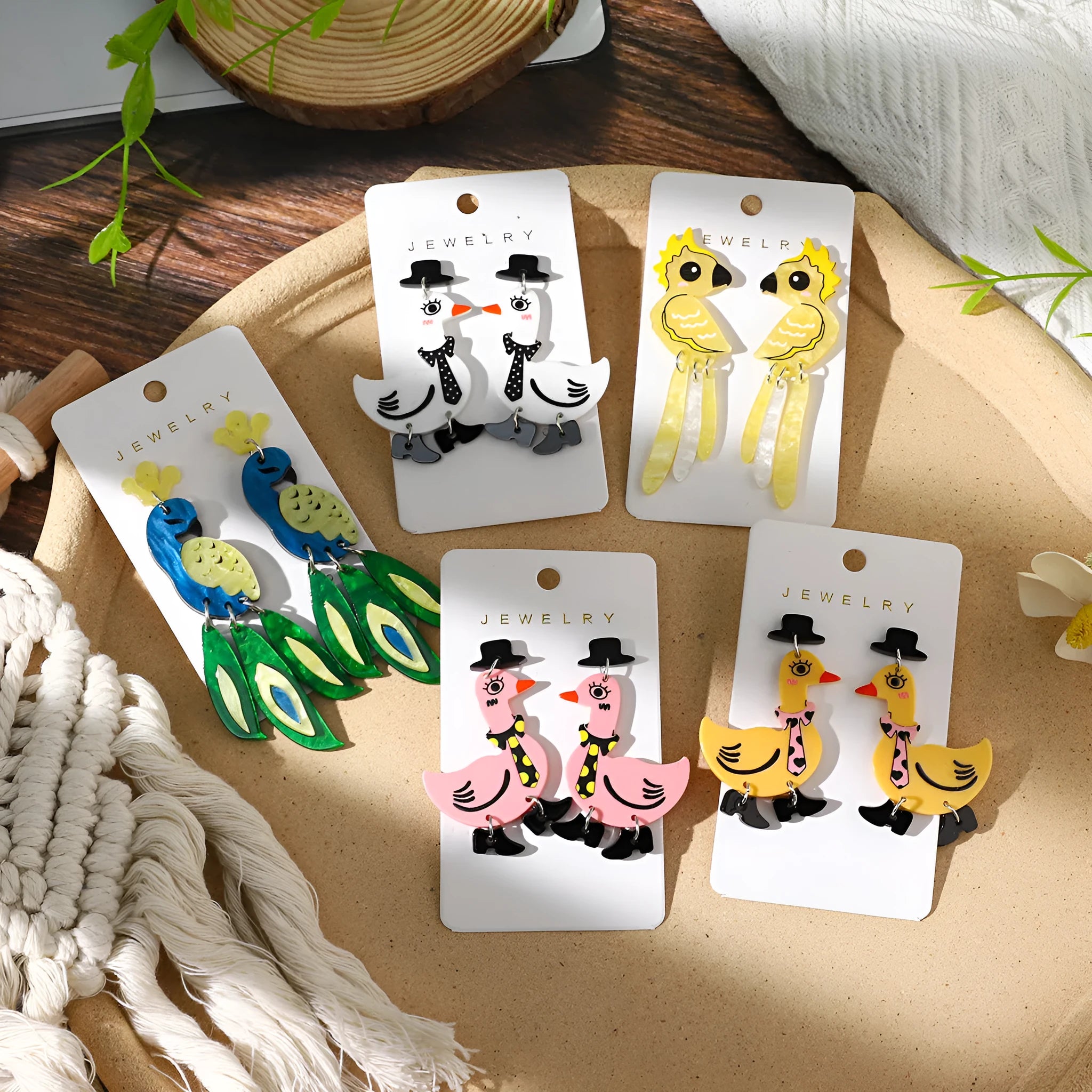 Three pairs of acrylic cartoon duck earrings in pink, white, and yellow on a light background