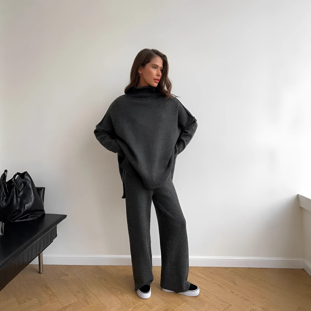 Women's dark grey acrylic knitted lounge suit with side-slit sweater and matching trousers on a hanger.