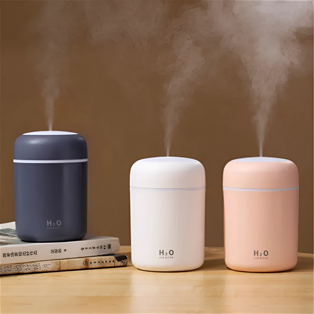 Pink portable car humidifier with coloured lights on a car dashboard next to a USB cable