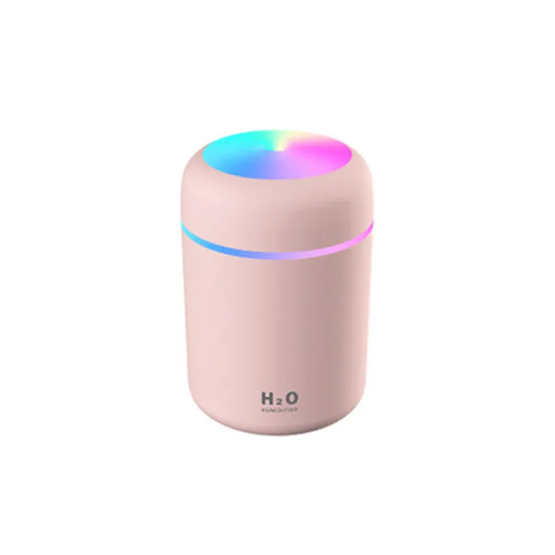 Pink portable car humidifier with coloured lights on a car dashboard next to a USB cable