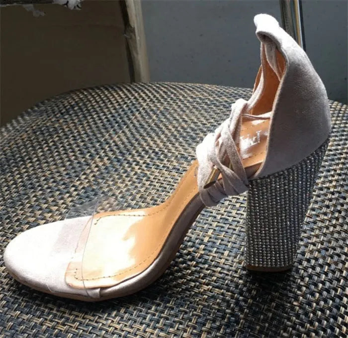 A pair of black plastic high heels with a pointed toe on a white background.