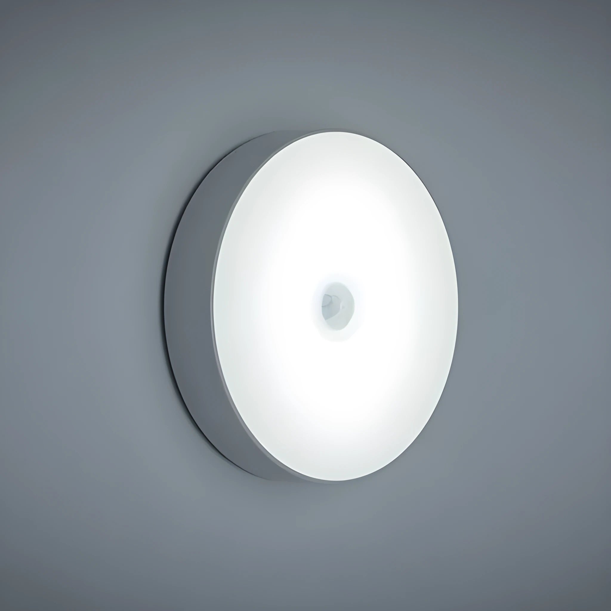 Compact round beige motion sensor LED night light with USB charging cable on a wooden surface