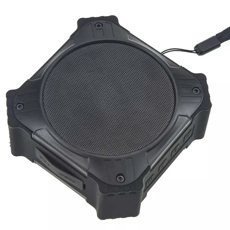 Compact black waterproof Bluetooth speaker with a wrist strap, shown next to a charging cable.