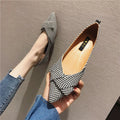 Women's black pointed toe slip-on shoes with a low flat heel on a plain background.