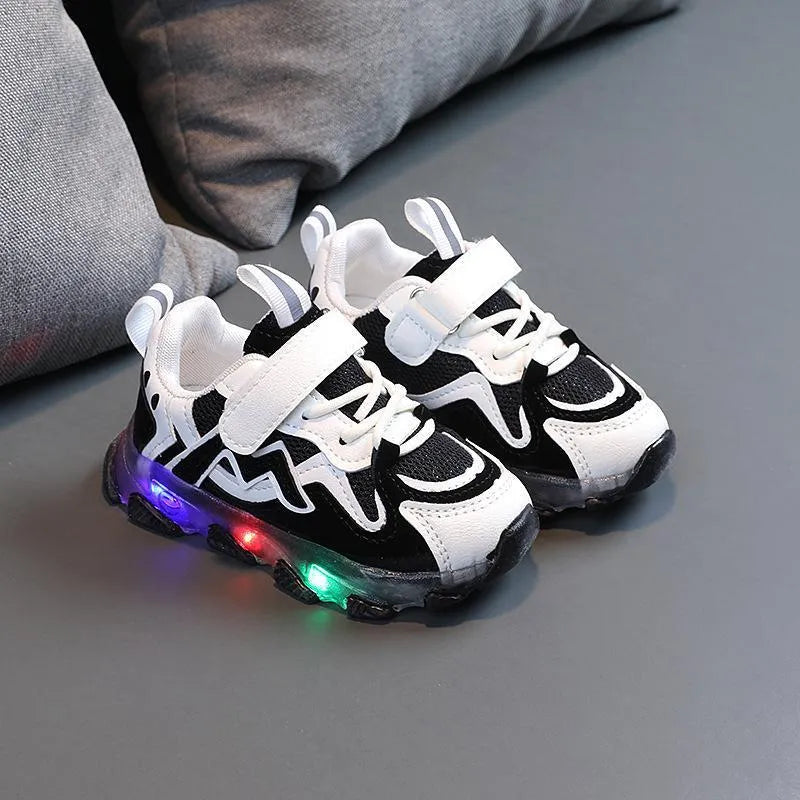 Kids black breathable mesh sneakers with Velcro strap and rubber sole on a grey background.