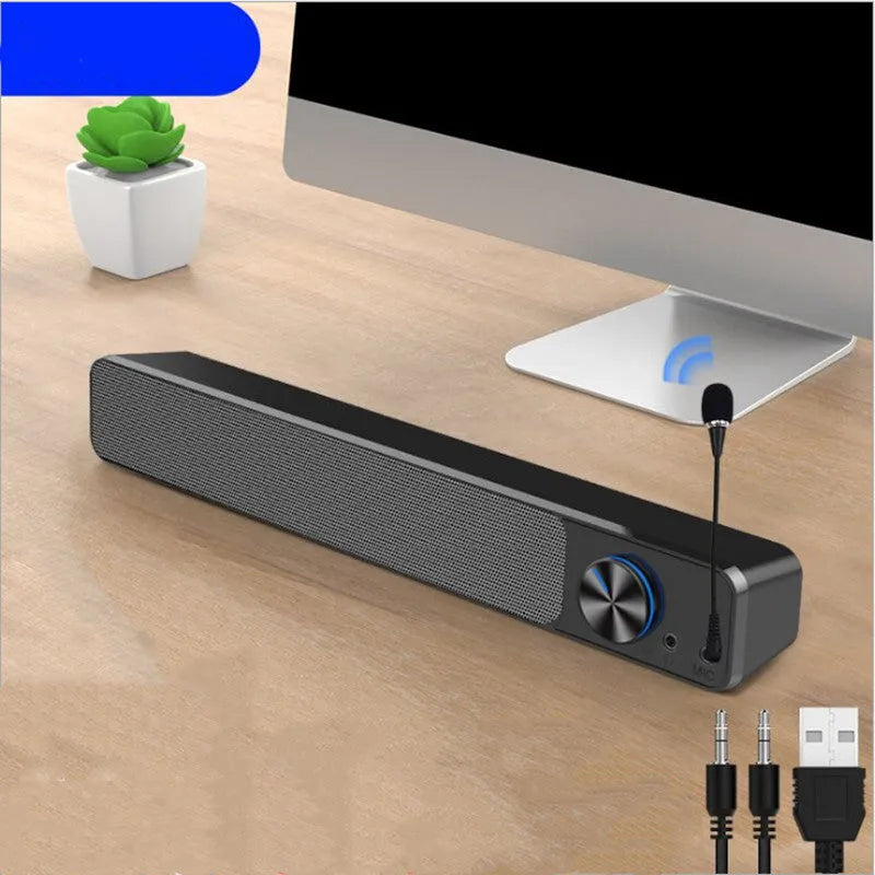 Compact black and white desktop computer speakers with USB cable on a wooden desk.