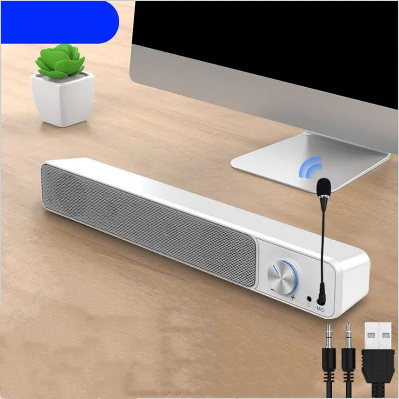 Compact black and white desktop computer speakers with USB cable on a wooden desk.