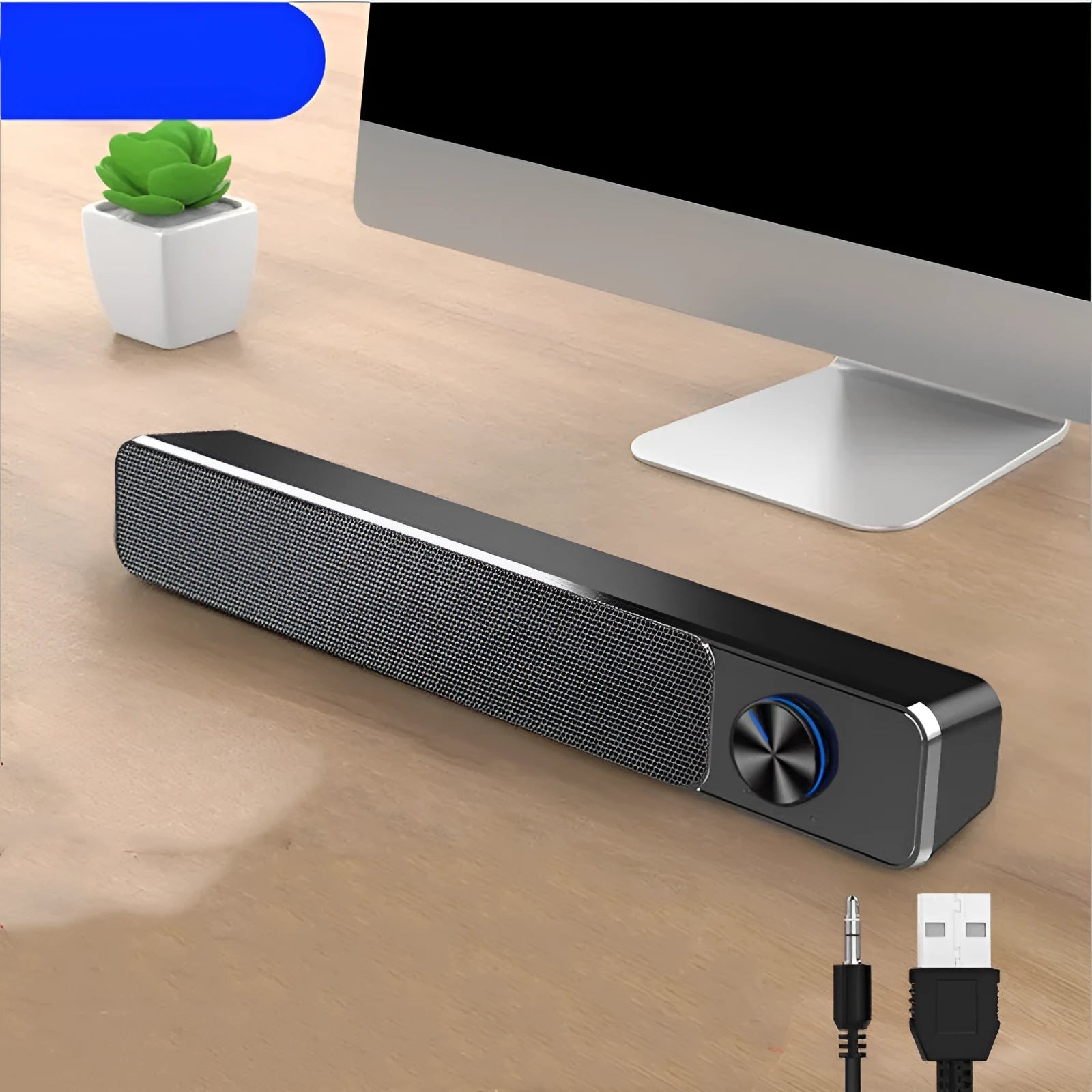 Compact black and white desktop computer speakers with USB cable on a wooden desk.
