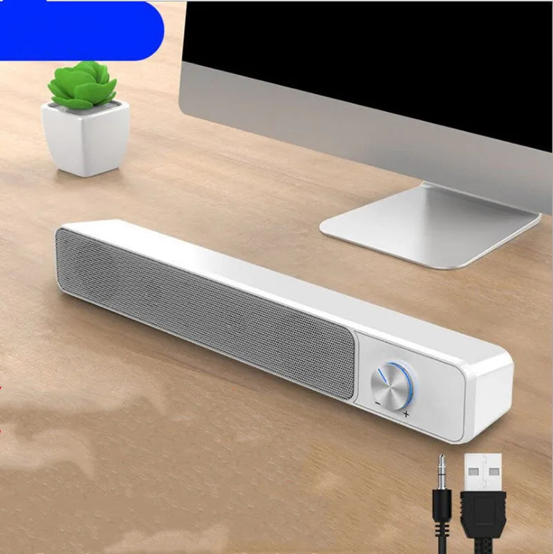 Compact black and white desktop computer speakers with USB cable on a wooden desk.