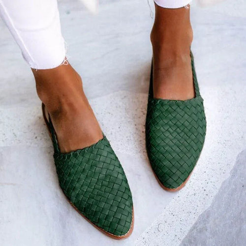 A pair of black baotou flat sandals with a buckle fastening and a pointed toe on a rubber sole.