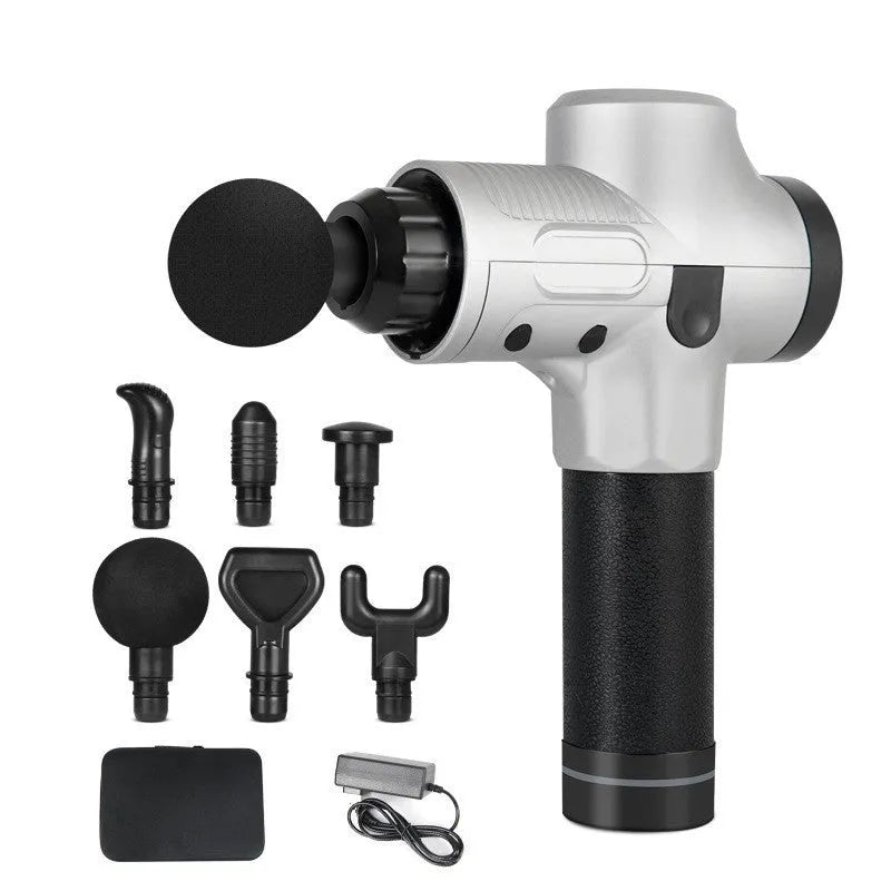 Black electric muscle massage gun with multiple attachment heads on a table.