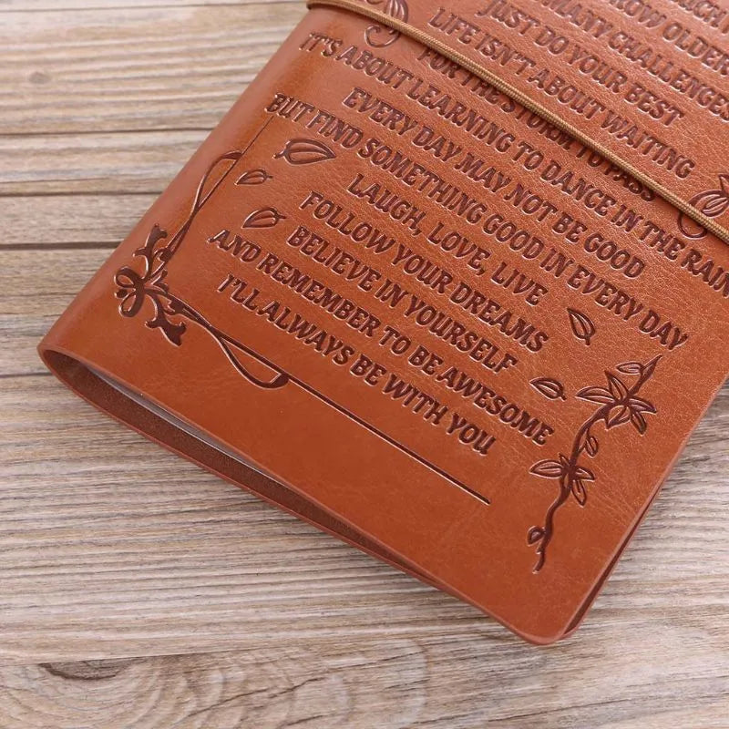 Brown leather hand ledger notebook with strap binding showing warm brown acid-free paper inside