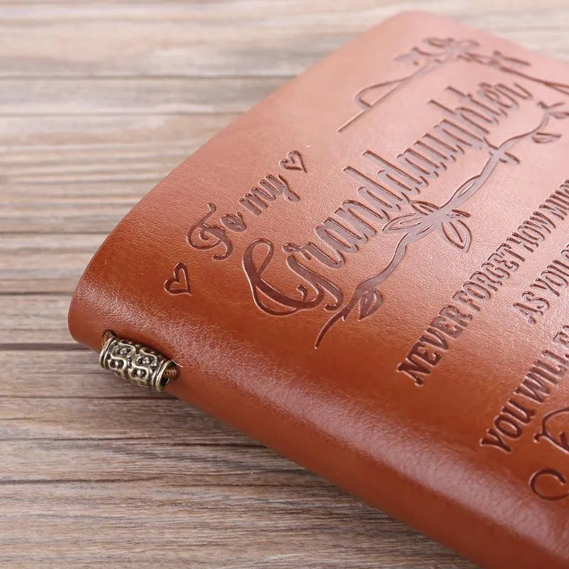 Brown leather hand ledger notebook with strap binding showing warm brown acid-free paper inside