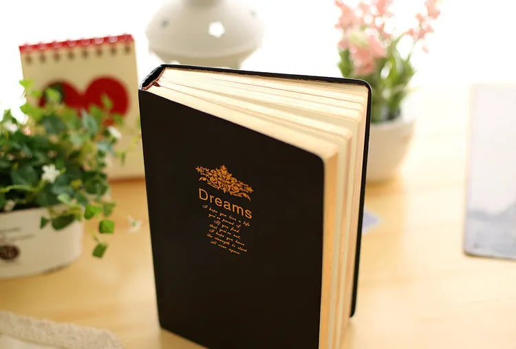 Jingu 25k thick imitation leather notebook open on a desk, showing its 35mm spine and A5 pages.