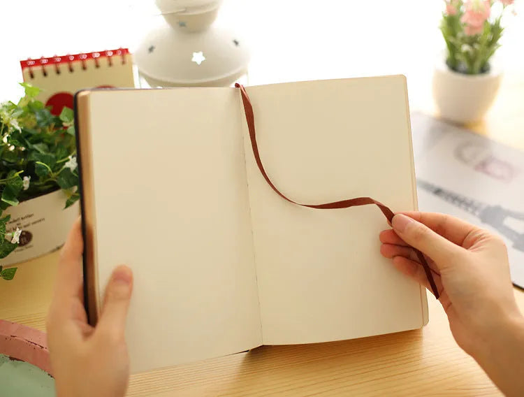 Jingu 25k thick imitation leather notebook open on a desk, showing its 35mm spine and A5 pages.