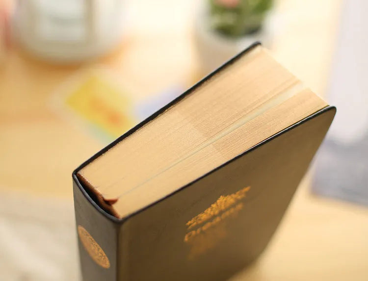 Jingu 25k thick imitation leather notebook open on a desk, showing its 35mm spine and A5 pages.