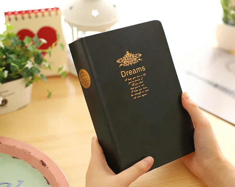 Jingu 25k thick imitation leather notebook open on a desk, showing its 35mm spine and A5 pages.