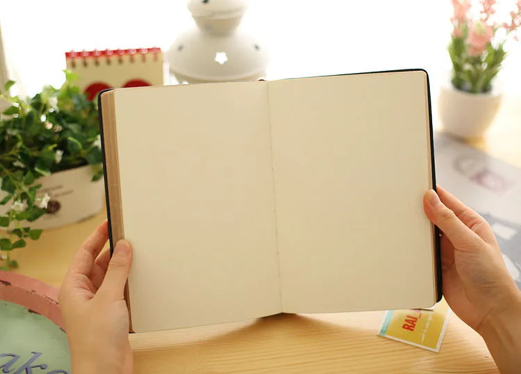 Jingu 25k thick imitation leather notebook open on a desk, showing its 35mm spine and A5 pages.
