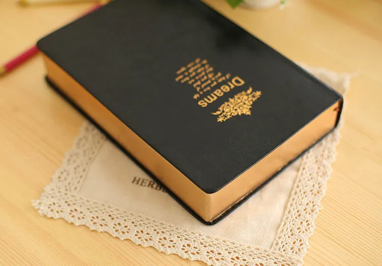 Jingu 25k thick imitation leather notebook open on a desk, showing its 35mm spine and A5 pages.