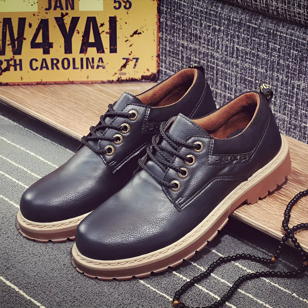 Men's black casual lace-up shoes with a round toe and flat rubber sole on a plain background.