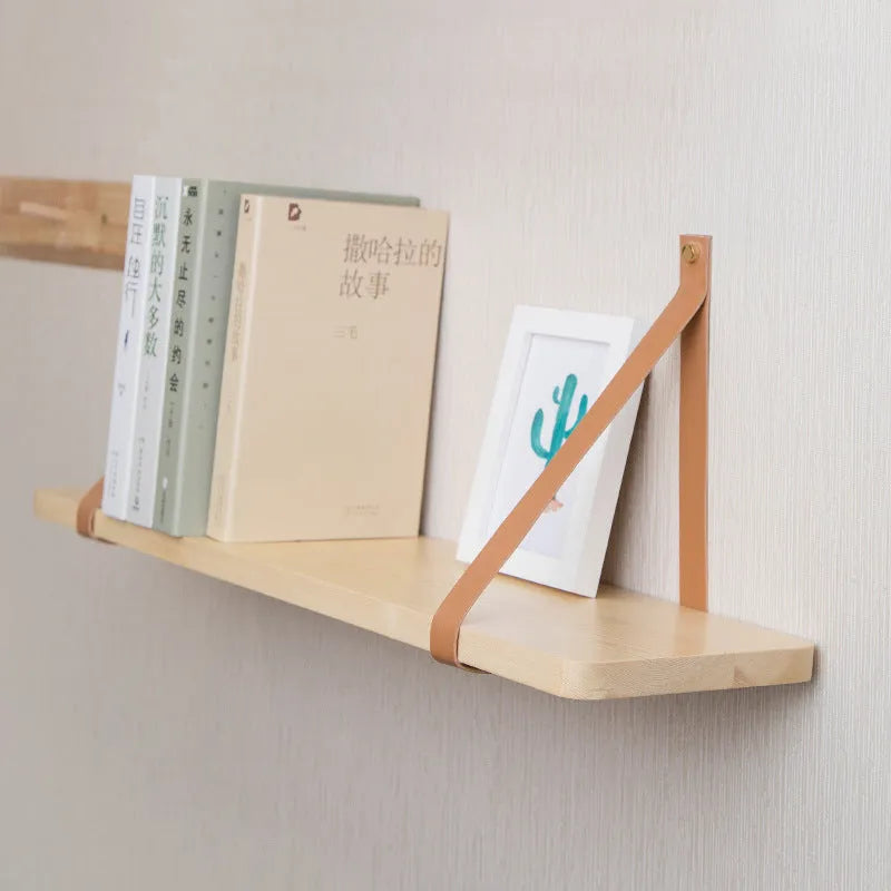 A narrow pine wood wall-mounted shelf unit for storing remote controls, books, and small items.