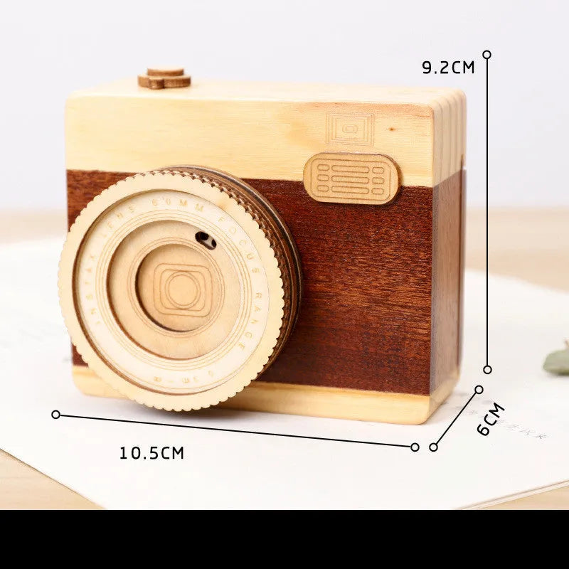 Wooden rotating camera music box in carton packaging, showing pine wood construction.