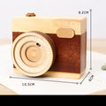 Wooden rotating camera music box in carton packaging, showing pine wood construction.