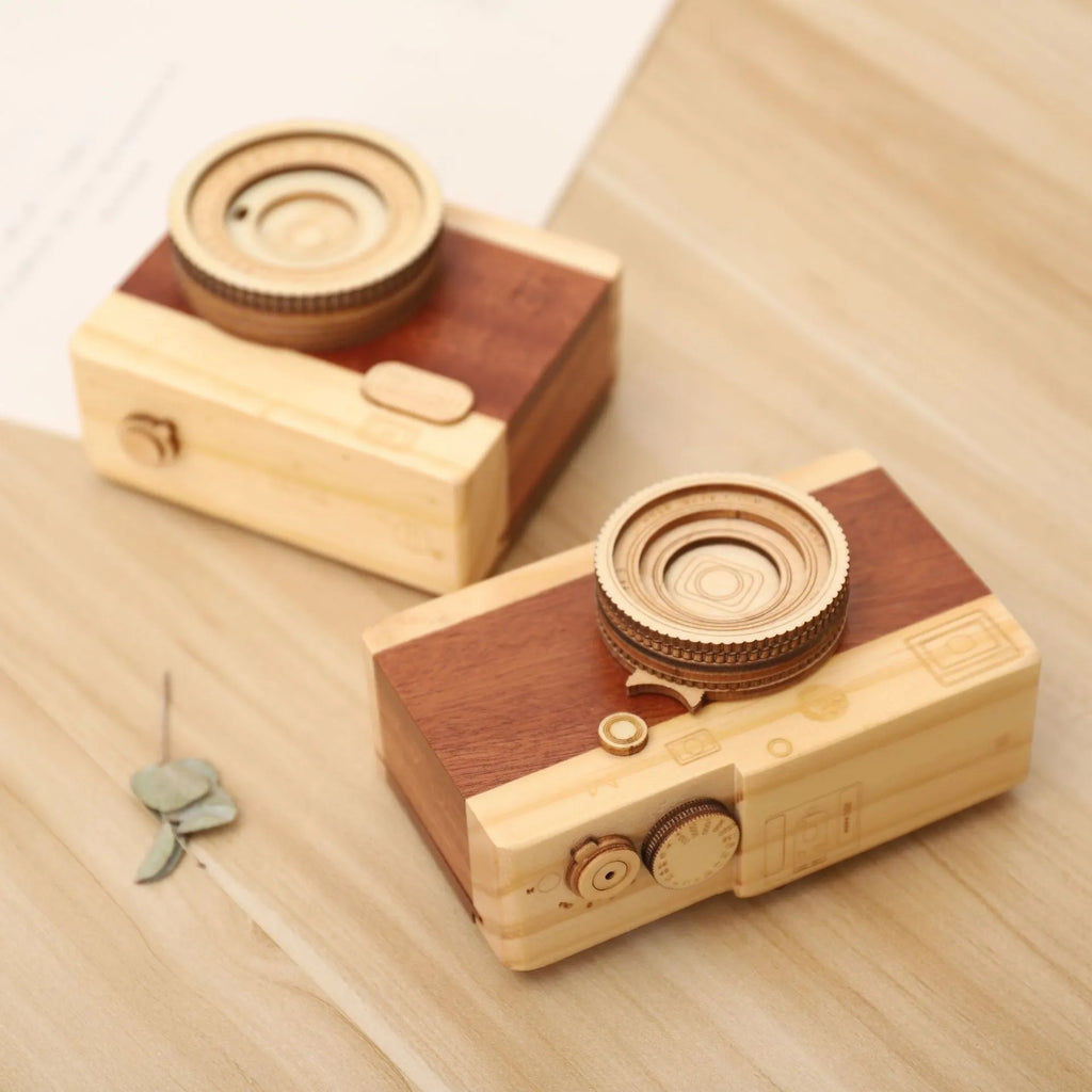 Wooden rotating camera music box in carton packaging, showing pine wood construction.