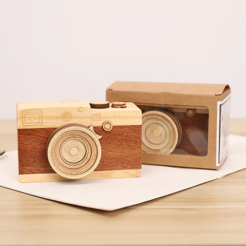Wooden rotating camera music box in carton packaging, showing pine wood construction.