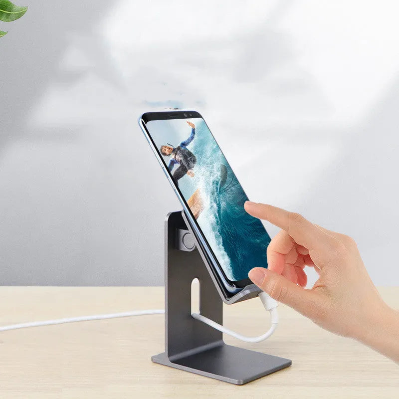 Dark Space Gray alloy mobile phone holder with a phone secured in its adjustable cradle on a wooden desk.