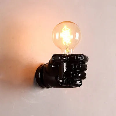 Creative resin fist sculpture wall lamp in black, mounted on a wall as a decorative light fixture.