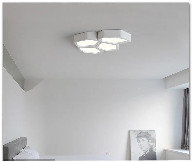 Geometric shaped iron LED light with black frame and remote control on a table.